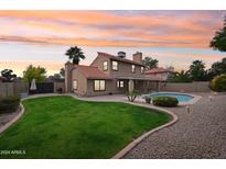 Stunning backyard oasis with a sparkling pool, lush lawn, and mature landscaping at 5544 E Paradise Ln, Scottsdale, AZ 85254