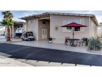 Tan home exterior with covered patio, golf cart, and red umbrella on patio table at 17200 W Bell Rd # 1218, Surprise, AZ 85374