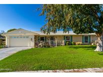 Ranch style home with a spacious lawn and attached garage at 10213 W Kingswood Cir, Sun City, AZ 85351