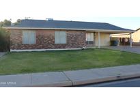 Brick home with carport, well-maintained lawn, and mature landscaping at 1650 S Windsor --, Mesa, AZ 85204