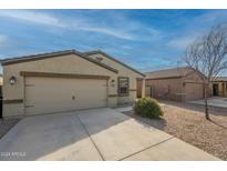 Tan house with a two-car garage and desert landscaping at 13157 E Chuparosa Ln, Florence, AZ 85132