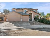 Two-story house with tan exterior, two-car garage, and landscaping at 2811 E Riviera Pl, Chandler, AZ 85249