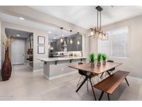 Kitchen island with seating and a dining table with modern chairs and bench at 31982 N 123Rd Ln, Peoria, AZ 85383