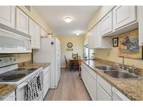 Long galley kitchen with white cabinets and granite counters at 10606 W Granada Dr, Sun City, AZ 85373