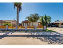 Cute bungalow with wood fence and mature palm tree in front at 2619 W Washington St, Phoenix, AZ 85009