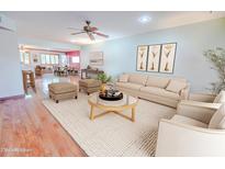 Bright living room with hardwood floors, featuring a beige sofa and coffee table at 9635 W Spanish Moss Ln, Sun City, AZ 85373