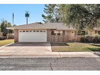 Brick ranch home with a white garage door and mature landscaping at 10205 W Royal Oak Rd, Sun City, AZ 85351