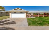 House exterior featuring a white garage door, well-manicured lawn, and a brick walkway at 10728 W Cheryl Dr, Sun City, AZ 85351