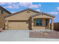 Tan house with two-car garage, landscaping, and a walkway at 11513 W Deanne Dr, Youngtown, AZ 85363