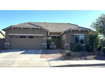 Tan two-story house with a three-car garage and nicely landscaped yard at 1099 E Tekoa Ave, Gilbert, AZ 85298