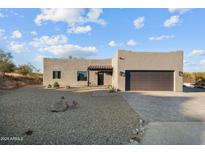 Single-story home with stucco exterior, dark brown garage door, and gravel landscaping at 44635 San Domingo Peak Trl, Morristown, AZ 85342