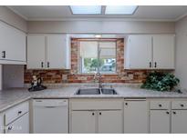 Kitchen with white cabinets, double sink, and a view to the backyard at 10610 W Saratoga Cir, Sun City, AZ 85351