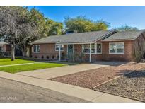 Brick home with landscaped lawn, driveway, and a teal front door at 2319 E Glenrosa Ave, Phoenix, AZ 85016