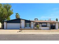 Ranch style home with white and dark blue exterior, two-car garage, and landscaped yard at 4447 W Carol Ave, Glendale, AZ 85302