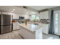 Bright, updated kitchen with stainless steel appliances, white cabinets, and large island at 17403 N 36Th St, Phoenix, AZ 85032