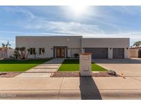 Modern, single-story home with a three-car garage and artificial turf at 5049 E Shaw Butte Dr, Scottsdale, AZ 85254