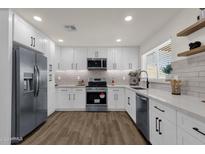 Modern kitchen with white cabinets, stainless steel appliances, and quartz countertops at 9437 N 63Rd Dr, Glendale, AZ 85302