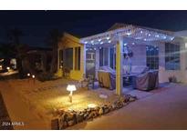 Inviting front yard with covered patio, string lights, and landscaping at night at 215 N Power Rd # 404, Mesa, AZ 85205