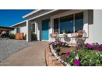 Inviting front yard with a blue door, charming walkway, and vibrant flowers at 2926 E Windrose Dr, Phoenix, AZ 85032