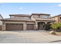 Inviting two-story home with a three-car garage, stone accents, and desert landscaping at 9622 S 46Th Ln, Laveen, AZ 85339