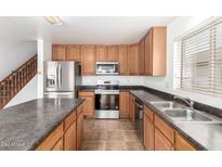 Modern kitchen features stainless appliances, wood cabinets, and an island at 21869 W Mohave St, Buckeye, AZ 85326