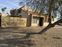 Tan stucco condo with tile roof, wooden fence, and a tree in front at 4766 W Rose Ln, Glendale, AZ 85301