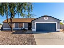 Single-story home with gray exterior, dark garage door, and a tree in front at 13525 S Burma Rd, Arizona City, AZ 85123