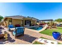 Inviting backyard oasis with a sparkling pool, patio furniture, and a pergola at 18174 W Wind Song Ave, Goodyear, AZ 85338