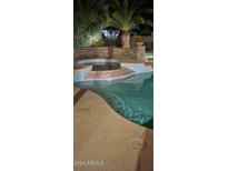 Inviting swimming pool with spa and waterfall feature at night at 18228 N San Salvador Ct, Surprise, AZ 85374