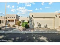 Tan stucco house with a two-car garage and landscaped front yard at 14444 W Moccasin Trl, Surprise, AZ 85374