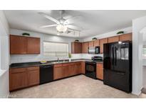 Modern kitchen features dark wood cabinets, black appliances, and tile flooring at 931 W Cedar Tree Dr, San Tan Valley, AZ 85143