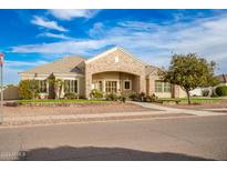 Front exterior of a single-story house featuring stone accents, lush landscaping, and an arched entryway at 21406 E Mewes N Rd, Queen Creek, AZ 85142