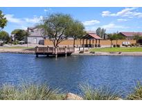 Scenic community lake with a wooden deck, ramadas, and green grass at 37028 W Prado St, Maricopa, AZ 85138