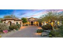 Inviting home exterior at dusk with paver driveway, stone accents, and desert landscaping at 36701 N Porta Nuova Rd, Scottsdale, AZ 85262