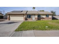 Single-Gathering home with attached garage, green lawn, and solar panels at 1906 N Evergreen St, Chandler, AZ 85225