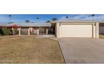 Front yard of a single-story home with attached garage, driveway, and landscaping at 10330 W Desert Forest Cir, Sun City, AZ 85351