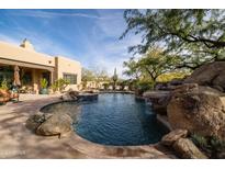Inviting pool with a rock waterfall feature and surrounding patio at 33296 N Vanishing Trl, Scottsdale, AZ 85266