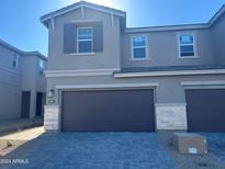 Modern two-story home with a dark-colored garage door and paver driveway at 5807 E Rose Garden Ln, Phoenix, AZ 85054