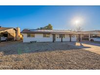 Front view of a single-story home with solar panels, gravel landscaping, and a covered porch at 7823 N 60Th Ave, Glendale, AZ 85301