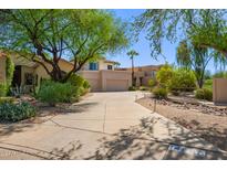 Inviting front yard with a paved driveway, lush landscaping, and desert plants at 14988 N 100Th Way, Scottsdale, AZ 85260