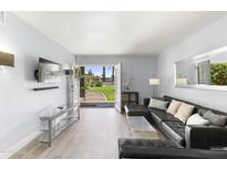 Living room with glass doors opening to a grassy backyard, leather sectional sofa, and modern glass coffee table at 6834 E 4Th St # 7, Scottsdale, AZ 85251