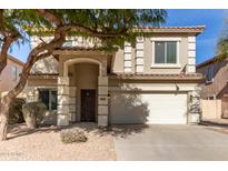 Two-story house with tan exterior, large windows, and a two-car garage at 44344 W Knauss Dr, Maricopa, AZ 85138