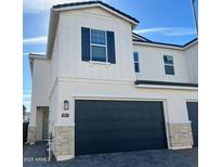 Two-story light beige home with a black garage door and stone accents at 5017 E Anderson Dr, Scottsdale, AZ 85254