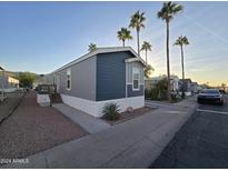 Gray manufactured home with a deck and carport, landscaped yard, and palm trees at 821 W Kachina Trl, Phoenix, AZ 85040