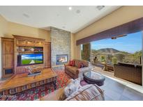 Spacious living room with stone fireplace and stunning mountain views at 10843 E La Junta Rd, Scottsdale, AZ 85255