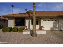 Front view of a light-colored brick home with a red tile roof, two red chairs, and a garage at 2310 S Farnsworth Dr # 10, Mesa, AZ 85209