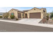 Single-story home with tan stucco exterior, brown garage doors, and landscaping at 18852 N 260Th Ln, Buckeye, AZ 85396