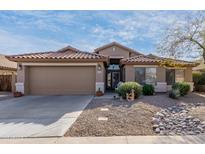 Tan house with tile roof, two-car garage, and desert landscaping at 42269 W Little Dr, Maricopa, AZ 85138