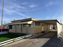 Tan mobile home with carport and artificial turf at 5201 W Camelback W Rd # D69, Phoenix, AZ 85031