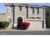 Tan two-story house with a red door and attached two-car garage at 9527 N 82Nd Ln, Peoria, AZ 85345